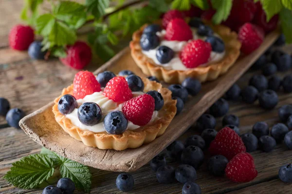Dessert tarts with raspberries and blueberries on a wooden tabl — Stock Photo, Image