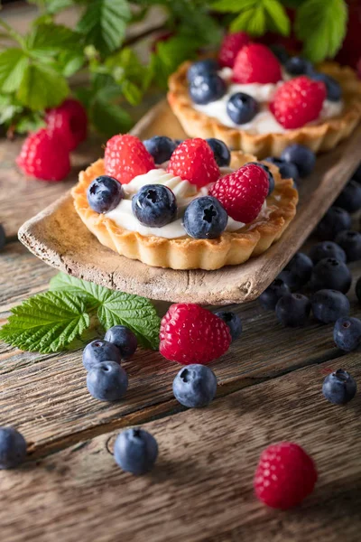 Десертные пироги с малиной и черникой на деревянной доске — стоковое фото