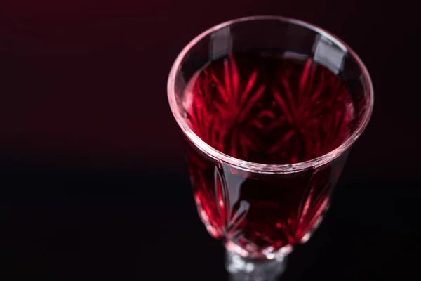 Крупним планом кришталевий келих з червоним вином на темному фоні . — стокове фото