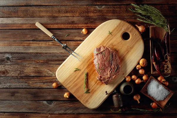 Nepečený steak v omáčce s kořením a rozmarýnem na starém dřevě — Stock fotografie