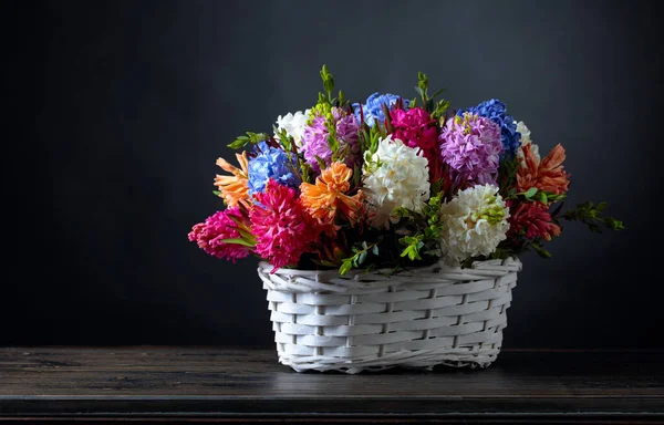 Bouquet of hyacinths in a white basket, dark background. — Stock Photo, Image