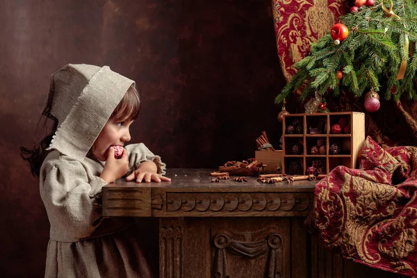 Klein meisje in een vintage linnen jurk in de buurt van de tafel met snoep — Stockfoto