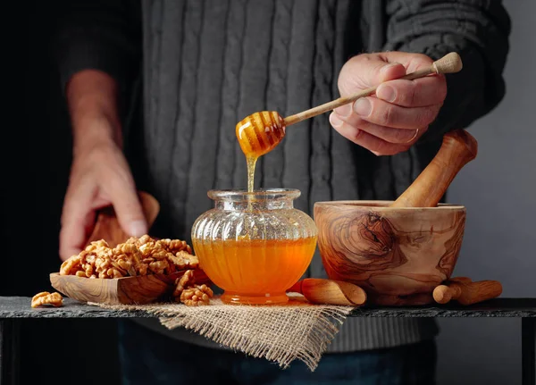 Man i en tröja förbereder en frukost med valnötter och honung. — Stockfoto