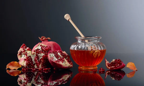 Frutta di melograno mature con miele e foglie asciugate su un blac — Foto Stock