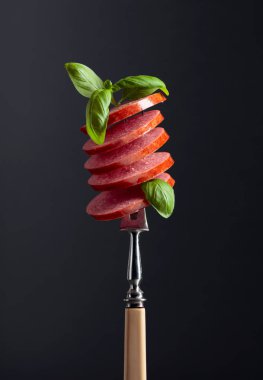 Dilimlenmiş sosis ve yeşil fesleğen yaprağı..