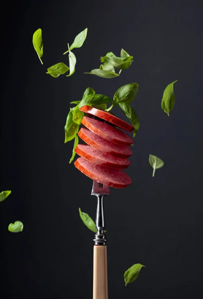 Salchicha ahumada en rodajas con hojas de albahaca verde . —  Fotos de Stock