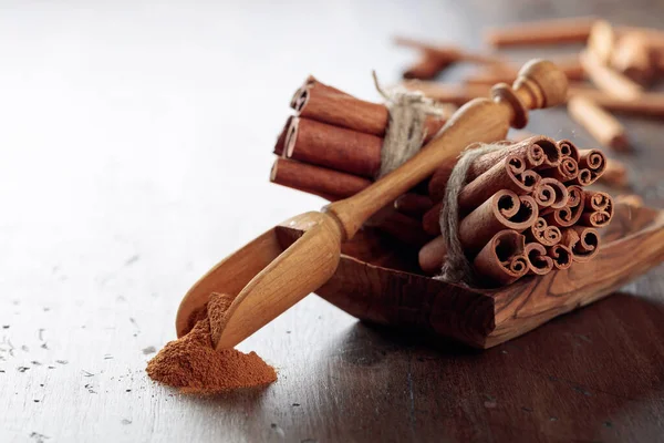 Cinnamon sticks and powder on a wooden table. — Stock Photo, Image