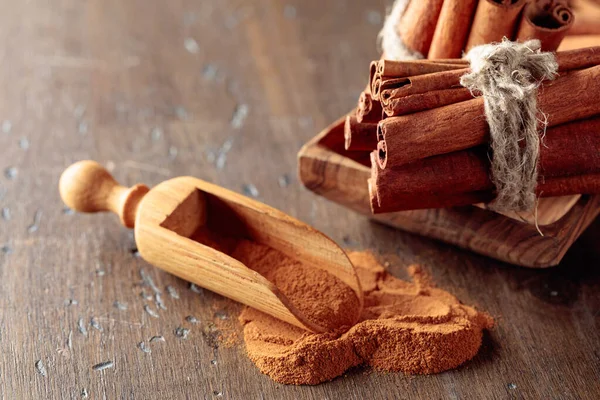 Varas de canela e pó em uma mesa de madeira. — Fotografia de Stock