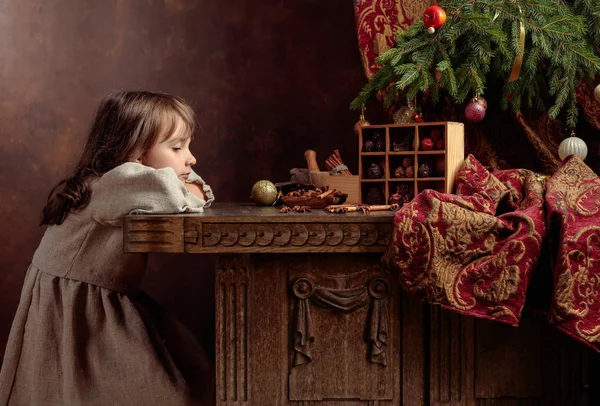 Klein meisje in een vintage linnen jurk in de buurt van de tafel met snoep — Stockfoto