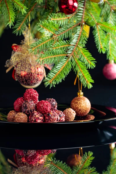 Truffes au chocolat sur une assiette noire et sapin de Noël . — Photo