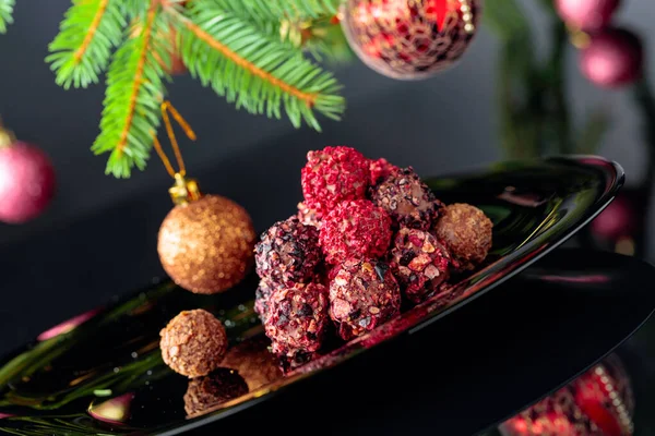 Truffes au chocolat sur une assiette noire et sapin de Noël . — Photo