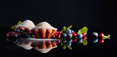 Yaban mersinli ve yaban mersinli kekler üzerine şeker tozu serpiştirilmiş.