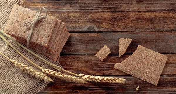 Rye crackers and ears on a old wooden table. — Stock Photo, Image