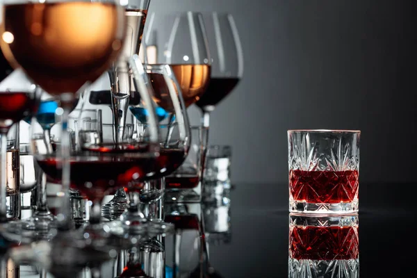 Набор различных алкогольных напитков в стаканах на черном отражении — стоковое фото