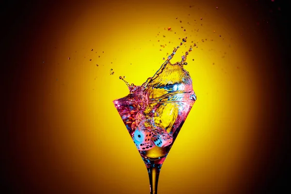 I dadi cadono in un bicchiere di martini. Cocktail colorato in vetro arguzia — Foto Stock