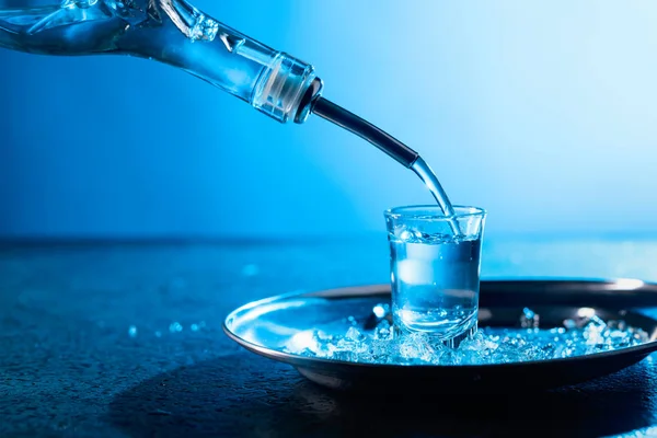 Wódka wlewa kieliszek z niebieskim podświetleniem. — Zdjęcie stockowe