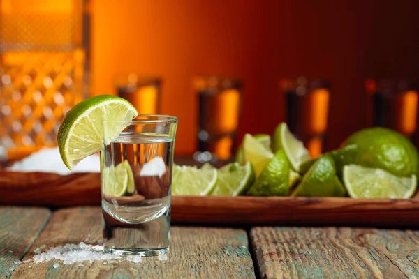 Tequila con sal y lima sobre un fondo de madera viejo . —  Fotos de Stock