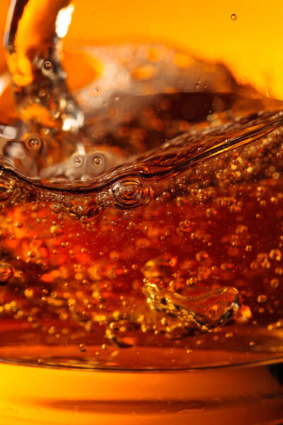 Whisky is poured into a glass with ice. 