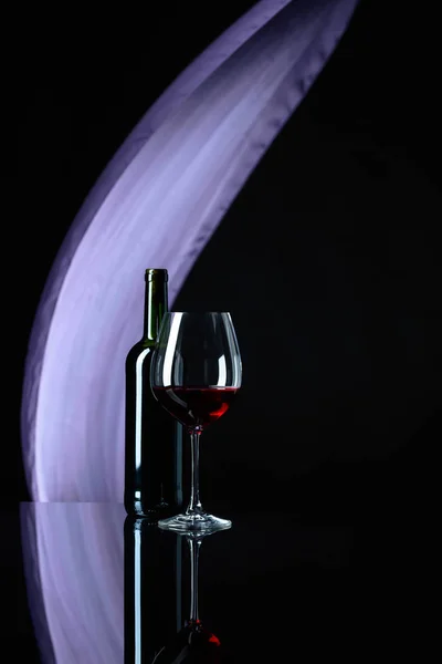 Wineglass en fles rode wijn op een zwarte reflecterende backgroun — Stockfoto