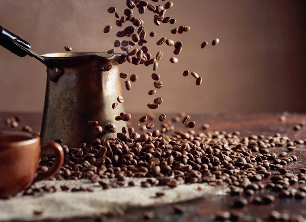 Falling coffee beans and old copper coffee maker. — Stock Photo, Image