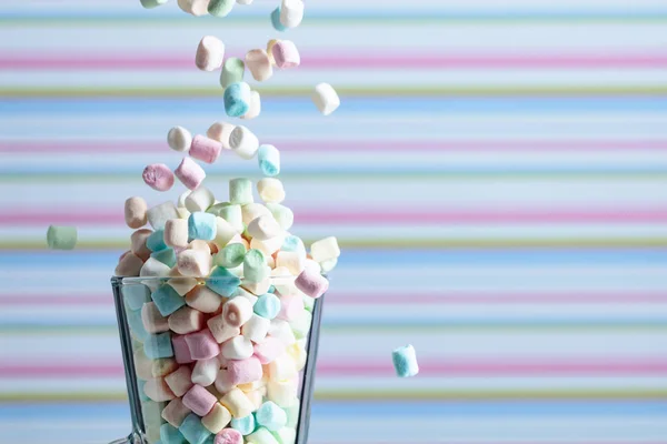 Os marshmallows caem na caneca. Pequenos marshmallows coloridos em vidro m — Fotografia de Stock