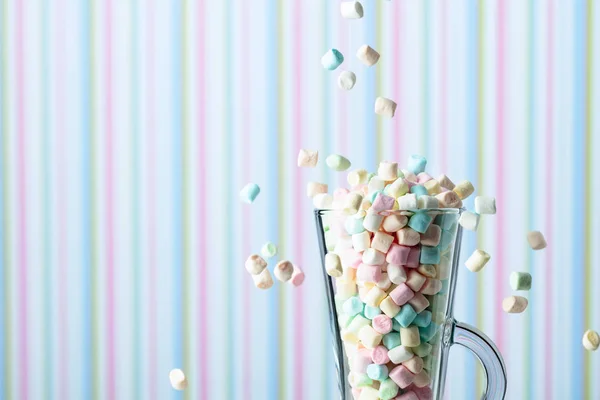 Marshmallows fall in mug. Small colorful marshmallows in glass m