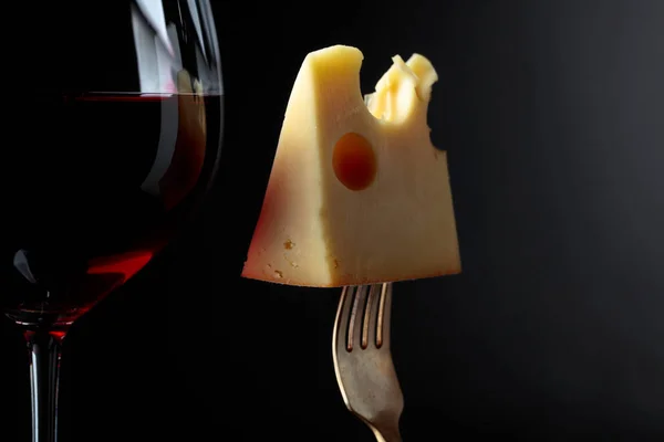 stock image  Maasdam cheese with red wine on a black background.