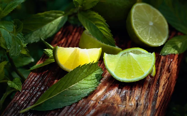 Rodajas de lima y hojas de menta sobre un fondo de madera viejo . —  Fotos de Stock