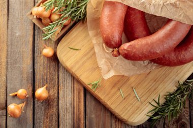 Eski ahşap bir masada ekmek ve baharatla tütsülenmiş sosis..