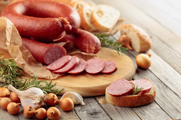 On a old wooden table sausage with bread, rosemary, onion and pe — Stock Photo, Image