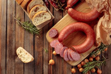 Eski ahşap bir masada ekmek ve baharatla tütsülenmiş sosis..