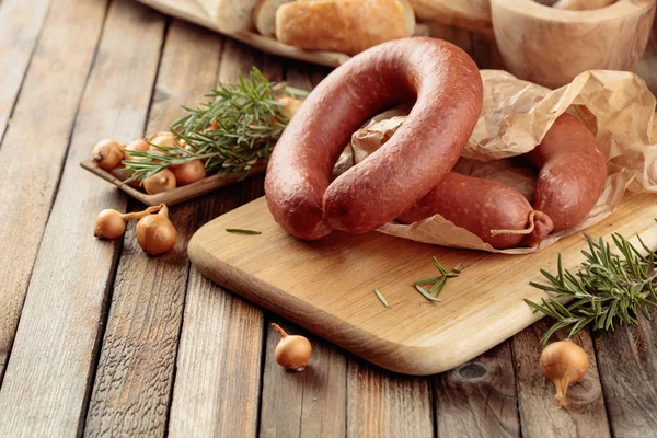 Gerookte worst met brood en specerijen op een oude houten tafel. — Stockfoto