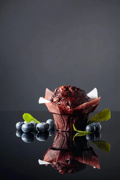 Шоколадный кекс с ягодами и мятой на черном отражающем пакете — стоковое фото