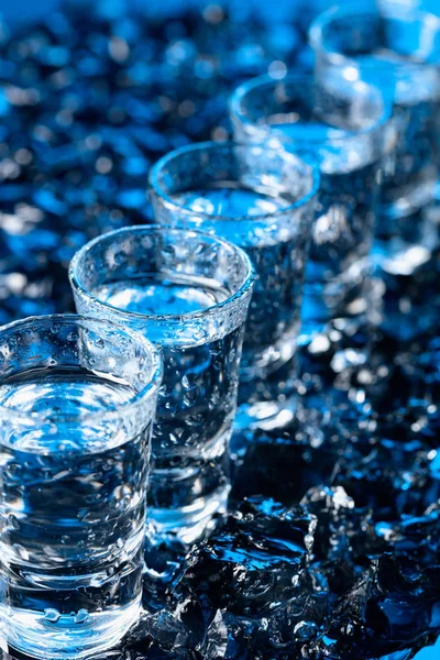 Damp glasses of vodka with ice on a black reflective background. — Stock Photo, Image