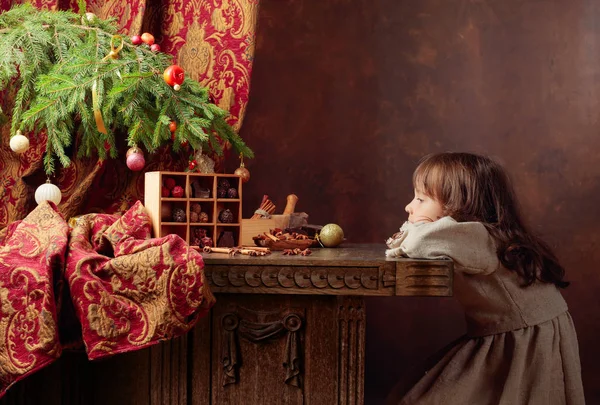 Klein meisje wacht op Kerstmis voor een vintage tafel — Stockfoto