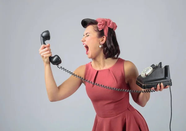 Привлекательная девушка в коралловом платье эмоционально разговаривает по телефону — стоковое фото