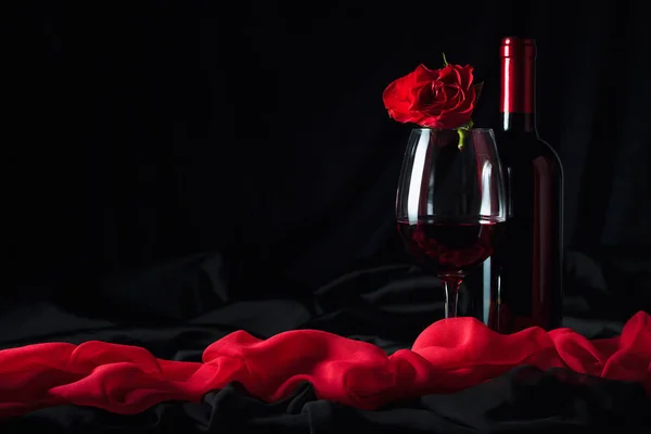 Vinho tinto e rosa vermelha no fundo preto . — Fotografia de Stock