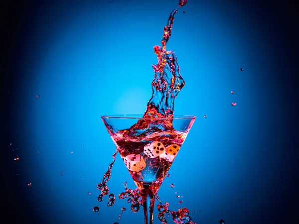 Dice fall in a glass of martini. Colourful cocktail in glass wit — Stock Photo, Image