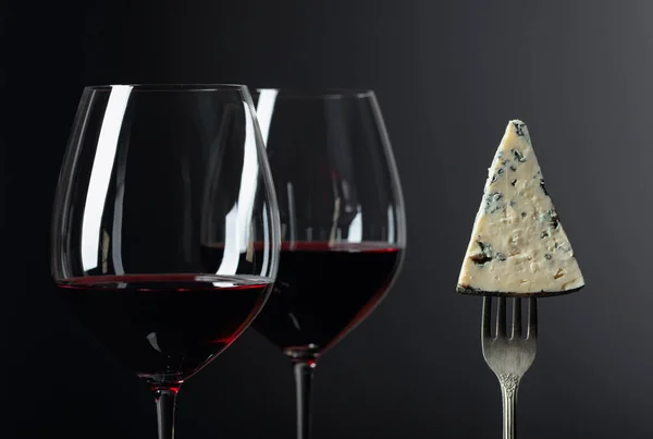 Pedaço de queijo azul em um garfo e vinho tinto . — Fotografia de Stock