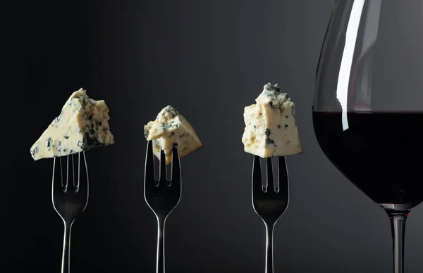 Pieces of blue cheese on a forks and red wine. — Stock Photo, Image