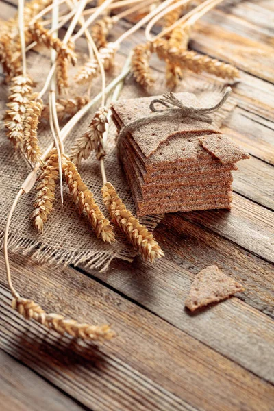 Rye crackers and ears on a old wooden table. — Stock Photo, Image