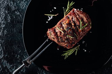 Biberiyeli ızgara biftek ve siyah tabakta tuz.
