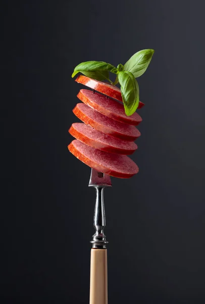 Salchicha ahumada en rodajas con hojas de albahaca verde . —  Fotos de Stock