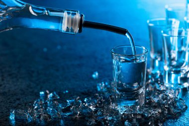 votka ile mavi arka plan ışığı yaktı bir bardak içine dökülür..