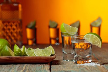 Eski ahşap arka planda tuz ve kireç ile tekila.