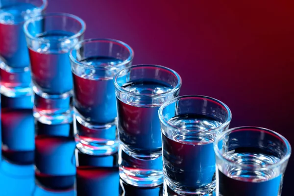 Vasos de vodka sobre fondo negro reflectante . — Foto de Stock