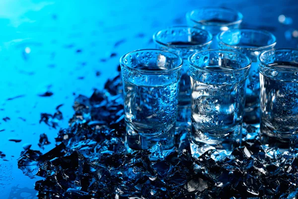 Copos úmidos de vodka com gelo em um fundo reflexivo preto . — Fotografia de Stock