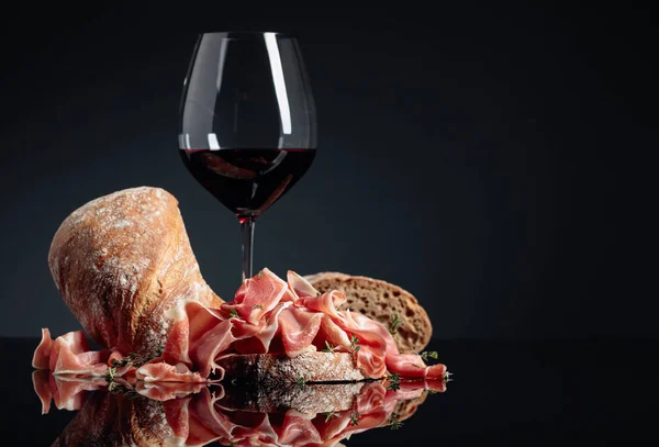 Prosciutto au ciabatta, vin rouge et thym sur fond noir — Photo