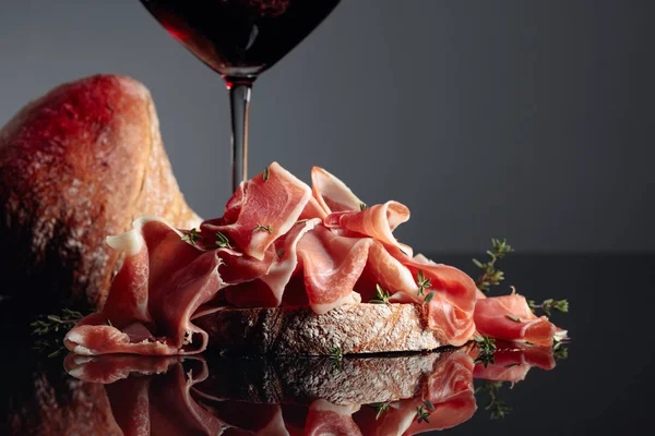 Prosciutto med ciabatta, rött vin och timjan på en svart backgrou — Stockfoto