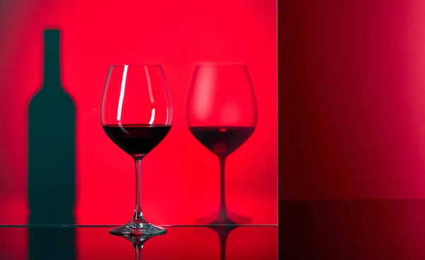 Пляшка і келихи червоного вина на чорному відбиваючому фоні . — стокове фото